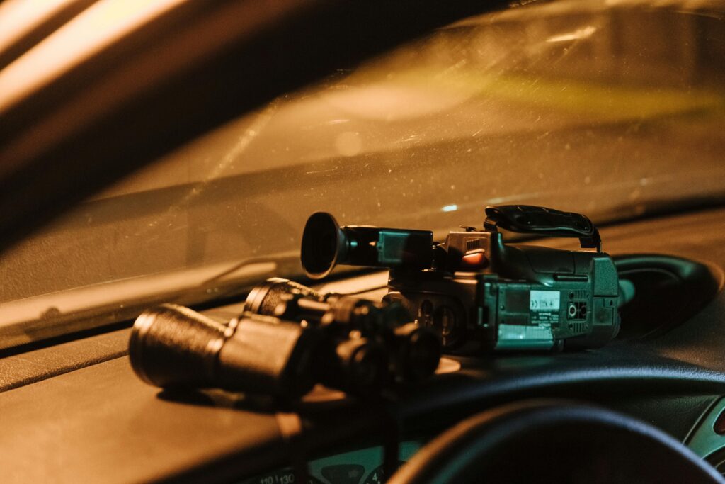 Membership Close-up of a camcorder and binoculars on car dashboard captured at night.